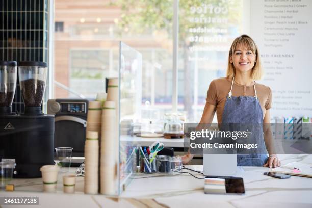 smiling female cashier at checkout counter with digital tablet in cafe - bangs ストックフォトと画像