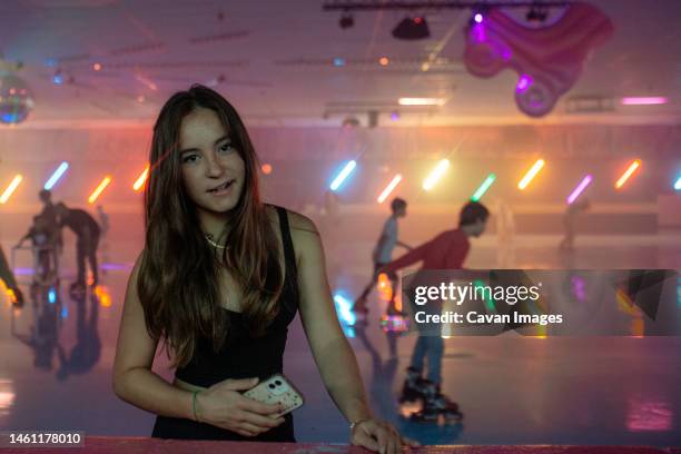 happy teen girl standing on side of roller skating rink - roller rink stock-fotos und bilder