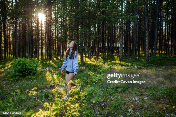 teen girl in forest holding a racket looking up - colter bay stock pictures, royalty-free photos & images