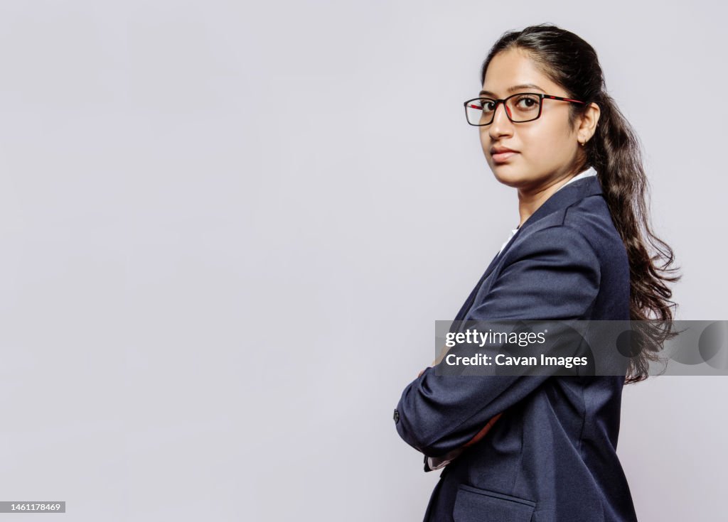 Side view of a college girl in blue suit hands folded and specs