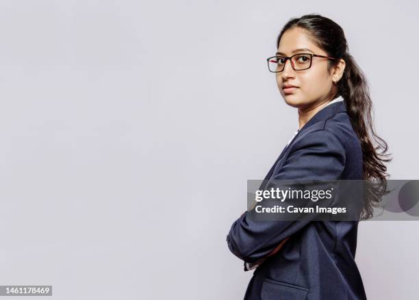 side view of a college girl in blue suit hands folded and specs - women standing against grey background stock pictures, royalty-free photos & images