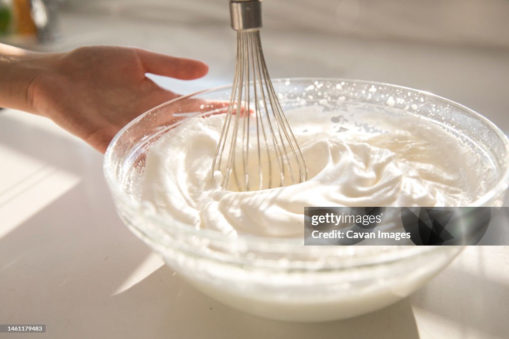Female hands using electric mixer to make whipped cream