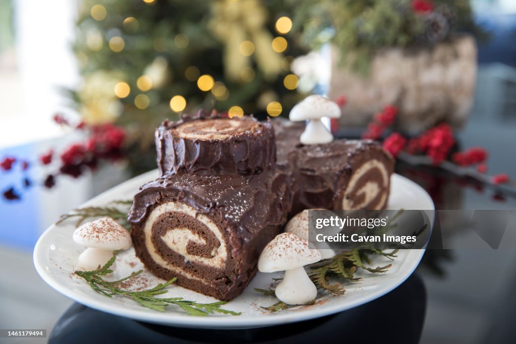 Decorated yule log with christmas tree in the background