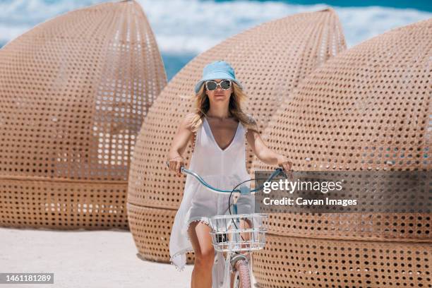 woman riding bicycle on the beach - thulusdhoo stock pictures, royalty-free photos & images