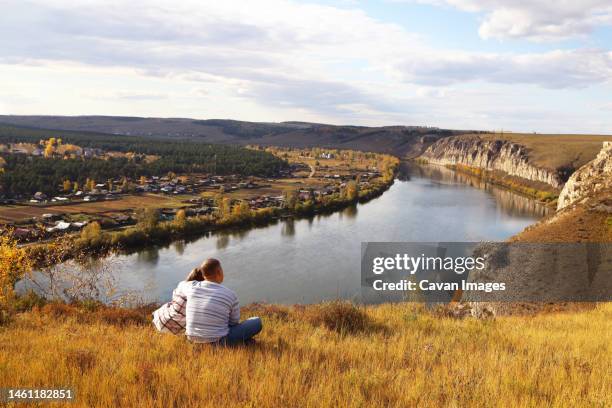 a married couple is sitting hugging on the riverbank - irkutsk stockfoto's en -beelden