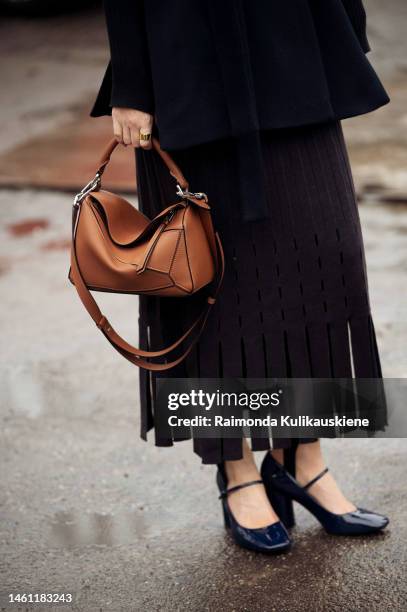 Guest wears black west, black skirt from tassels, brown bag, and black balaclava outside Aeron during the Copenhagen Fashion Week Autumn/Winter 2023...