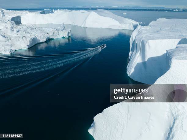 small boat near big icebergs from aerial point of view - ilulissat stock pictures, royalty-free photos & images