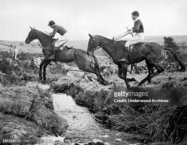 Two horses jumping over a creek in the Spooners Harriers Point to Point races at Dunnabridge in Dartmoor, Princetown, England, April 19, 1934.