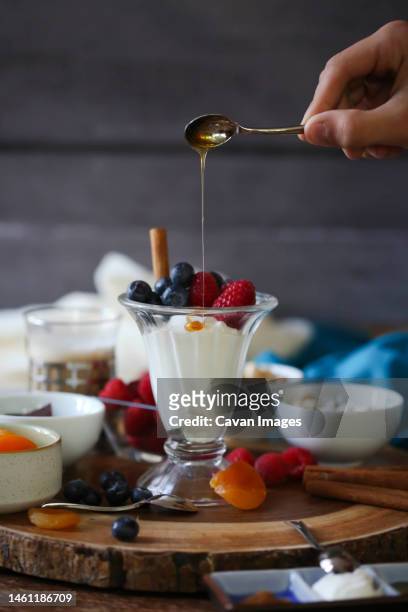 fruit and yogurt parfait with dripping honey on wood background - fruit parfait stock pictures, royalty-free photos & images
