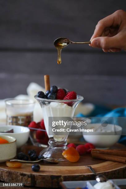 honey dripping from spoon onto fruit and yogurt parfait - fruit parfait stock pictures, royalty-free photos & images