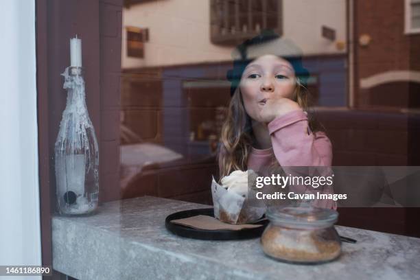 young girl sat in a cafe eating cake and drinking hot chocolate - winchester england stock-fotos und bilder