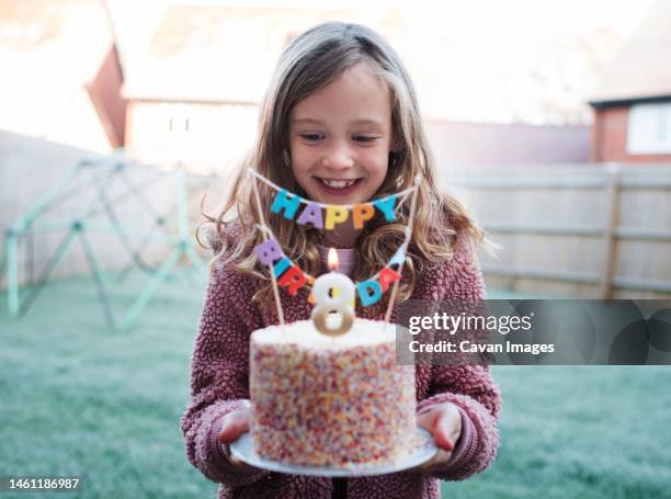 girl happily holding a 8th birthday cake on her birthday - kindergeburtstag stock-fotos und bilder