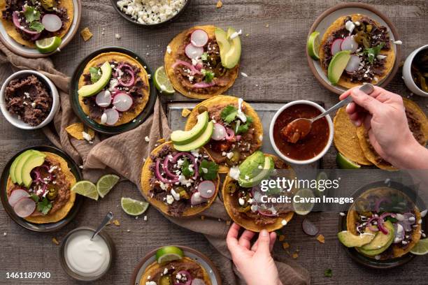 person adding salsa to a tostada - tostada stock pictures, royalty-free photos & images