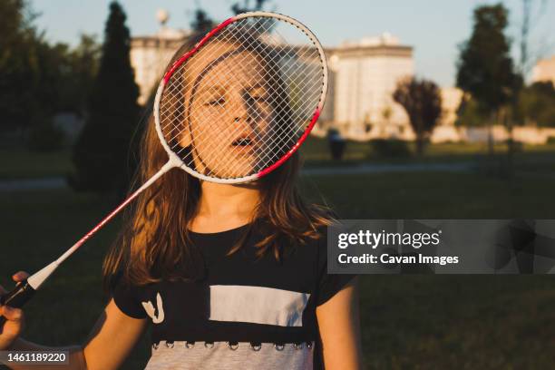 portrait of girl looking through badminton racket at the park - badminton stock pictures, royalty-free photos & images