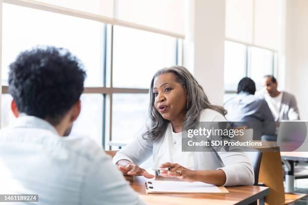 retired volunteer accountant helps young man with taxes - job fair stock pictures, royalty-free photos & images