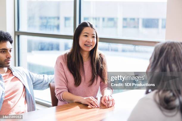 with angry husband sitting nearby, woman smiles at counselor - angry couple arab stock pictures, royalty-free photos & images