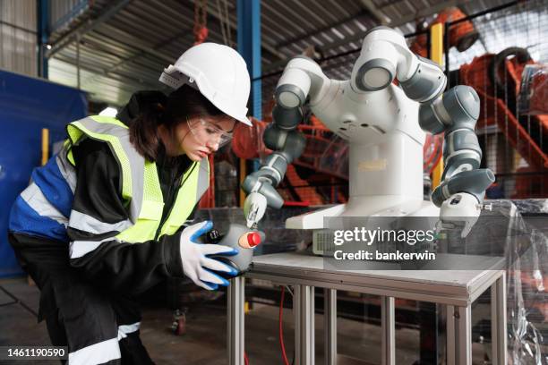 ingenieurin steuert roboter in der fabrik - roboterarm stock-fotos und bilder