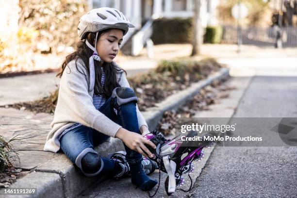 young girl putting on roller blades in front of her home - inline skate stock pictures, royalty-free photos & images