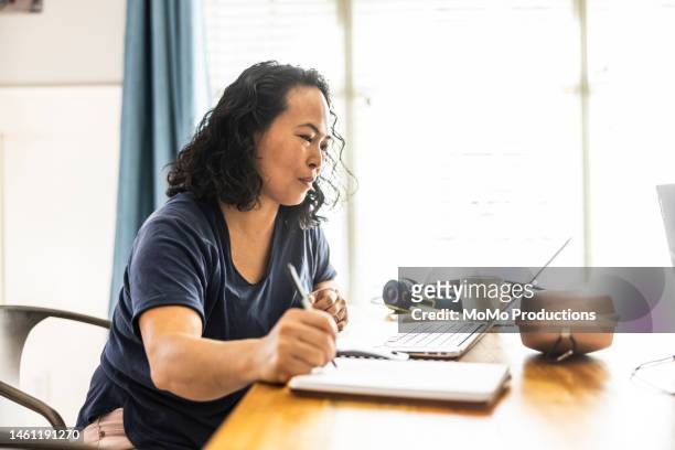 woman working from home at dining room table - pacific islander ethnicity stock pictures, royalty-free photos & images