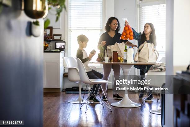 mother and children unloading groceries - latin american and hispanic shopping bags stock pictures, royalty-free photos & images