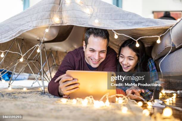 father and daughter watching a movie on digital tablet in homemade fort - hulu fotografías e imágenes de stock