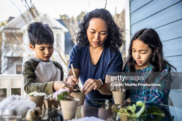 mother and children planting seedlings  in small planting pots - asian single mother stock pictures, royalty-free photos & images