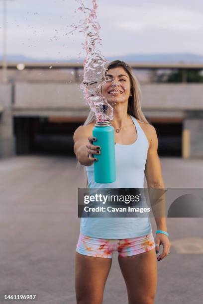 fitness coach splashing drink out of water bottle outside while - saint georges college stock pictures, royalty-free photos & images