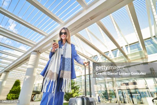 cheerful woman using smartphone in airport terrace - hdr belden stockfoto's en -beelden