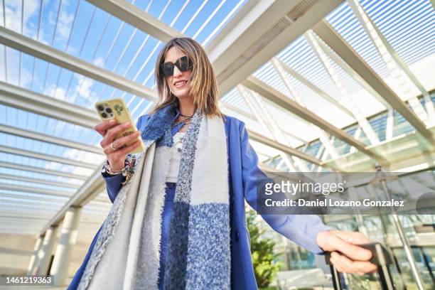 cheerful woman using smartphone in airport terrace - hdr belden stockfoto's en -beelden