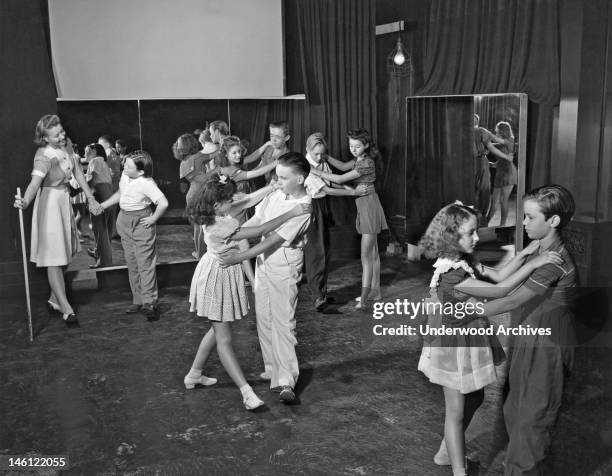 Studio Teacher Jeanette Bates gives a folk dancing lesson on the lot of Metro-Goldwyn-Mayer Studios to young actors who still have to go to school,...