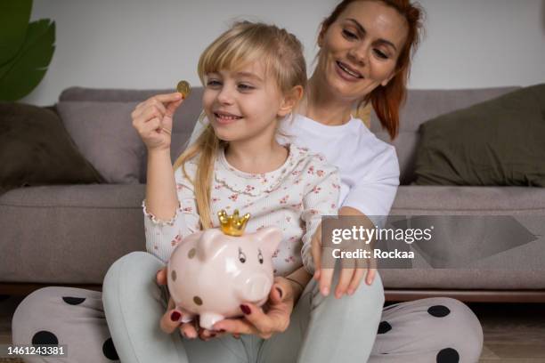 happy family inserting money into piggy bank - save our future babies stock pictures, royalty-free photos & images