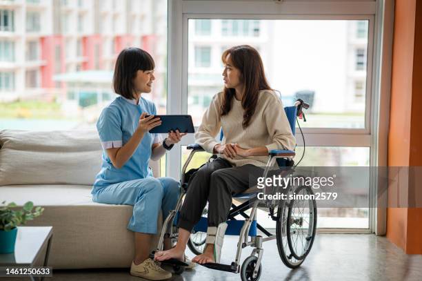 young female podiatric physician interpreting x-ray image to female patient broken leg with ankle brace while patient sitting on wheelchair at the hospital - foundation conversations screening of get out stock pictures, royalty-free photos & images
