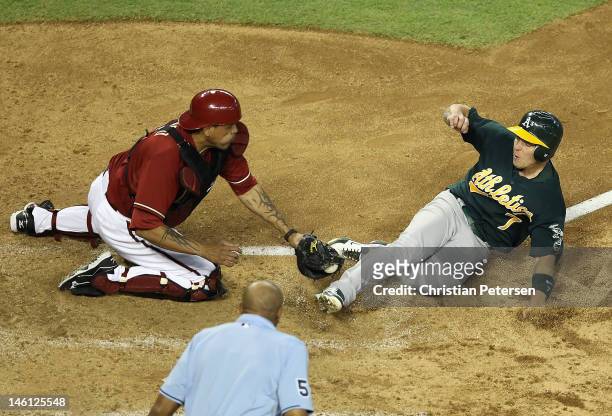 Brandon Inge of the Oakland Athletics safely slides in to score a run past the tag from catcher Henry Blanco of the Arizona Diamondbacks during the...