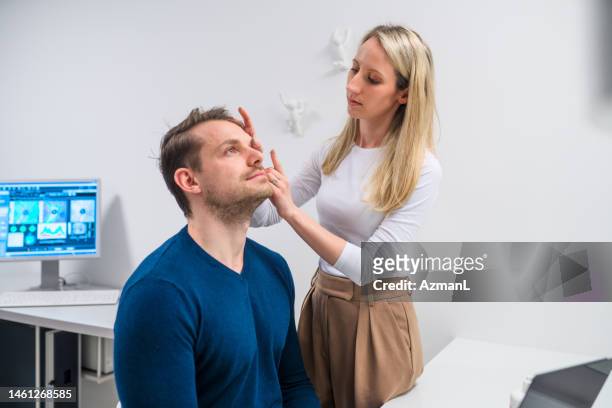 concentrated female optician using her hands on contact lenses for a client - lente de contacto imagens e fotografias de stock