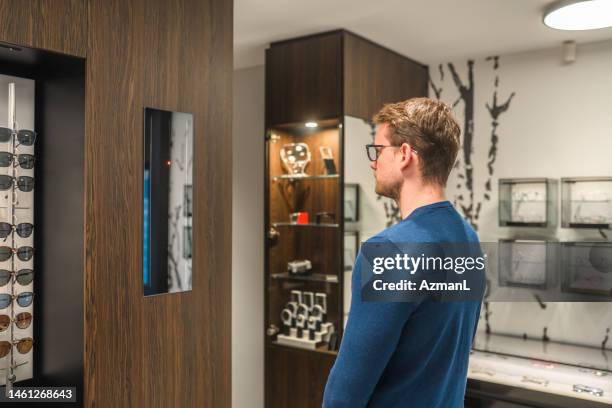 stylish and modern optic store with a male client - choosing eyeglasses stock pictures, royalty-free photos & images