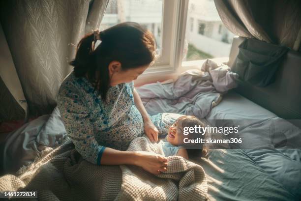 high-angle view asian mother pregnant  lying down and playing with daughter on the cozy bed in early morning domestic life - family time stock pictures, royalty-free photos & images