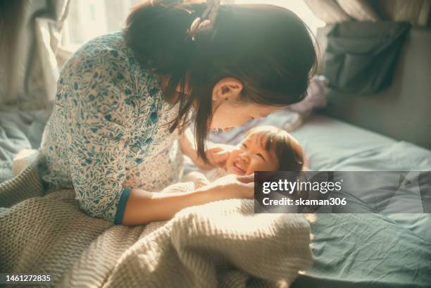 beautiful moment asian mother pregnant and playing with daughter on the bed  domestic life - emotionale momente geburt stock-fotos und bilder