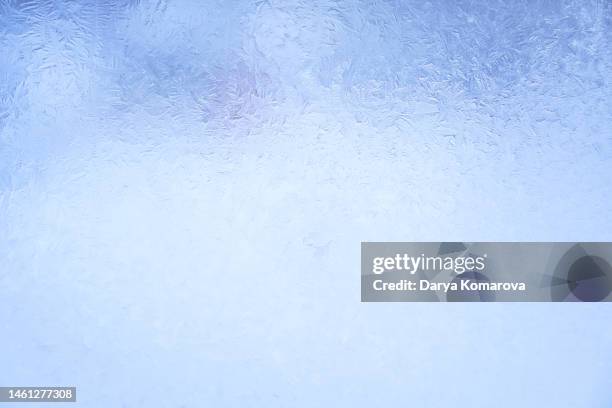 beautiful frosty pattern on the glass in the window. blue background with copy space. - frozen stock photos et images de collection