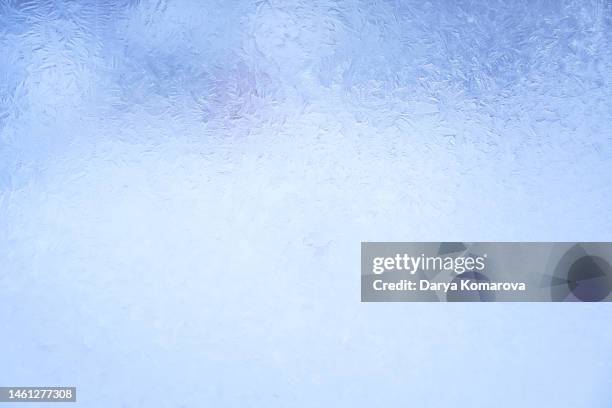 beautiful frosty pattern on the glass in the window. blue background with copy space. - frost stock pictures, royalty-free photos & images