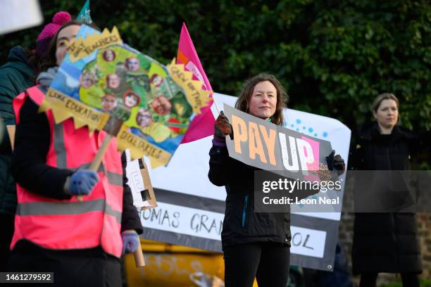 Teachers and supporters wave flags and hold placards as they picket outside Bishop Thomas Grant school during a day of national strikes by many...