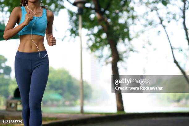 body part of healthy woman wearing sport clothing jogging exercise  in the park - asian six pack photos et images de collection