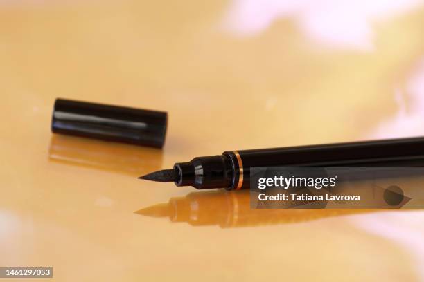 close up of black opened eyeliner on glossy colorful background. cosmetics, beauty industry concept. minimalistic layout - eyeliner ストックフォトと画像