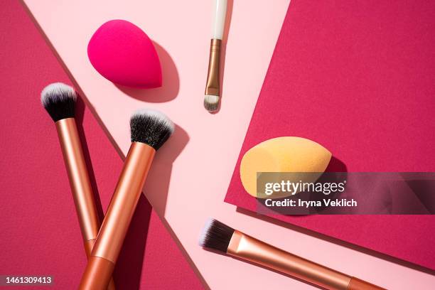 set of multi-functional makeup brush on pastel pink and  viva magenta color of the 2023 year background. face foundation application tool and makeup products, beauty blender sponges. - multi tool stock-fotos und bilder