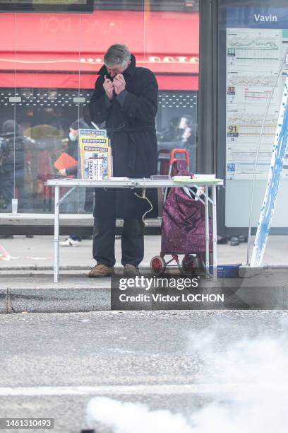 Un homme distribuant des magazines "Médiacritiques" se protège du gaz lacrymogène dans un abri-bus de la stattion "Vavin" lors de la manifestation...