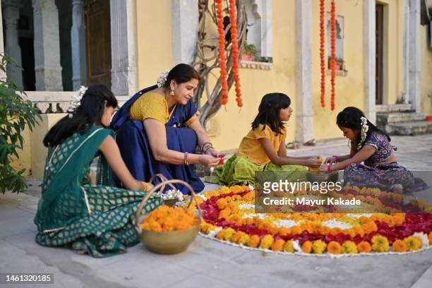 grandmother making flower rangoli with her grandchildren - preparation of gudi padwa festival stock pictures, royalty-free photos & images