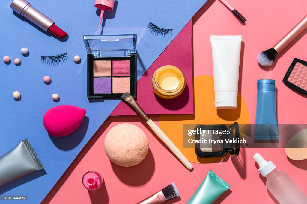 Set of Beauty Products Laid Out on a Multi-Color Background. Cosmetic Make-up products for a woman Make-Up Brush, Red Lipstick, False Eyelashes, Face Powder Blush Palette, Eyeshadow, Face Cream Hand Cream, Beauty Blender Sponges, Face Serum and Lip Balm.