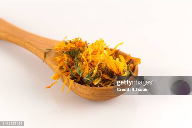 calendula flowewr tea for infusion in wooden spoon on white background - pot marigold stock pictures, royalty-free photos & images