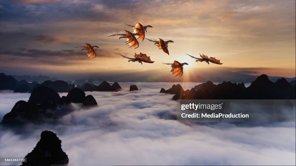 Flock of dragons flying over rolling clouds at sunrise