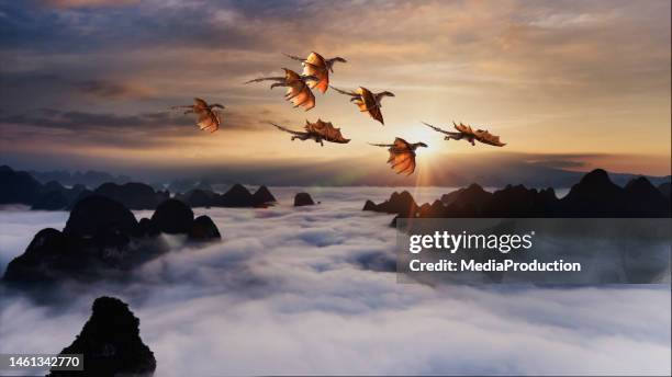 flock of dragons flying over rolling clouds at sunrise - draak fictieve figuren stockfoto's en -beelden