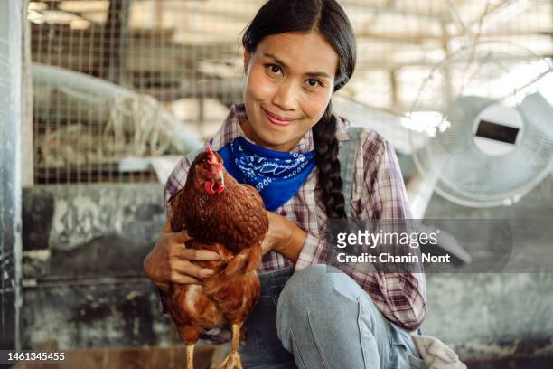 happy organic farmer holds chicken in his arms in front of hen house - woman eating chicken photos et images de collection